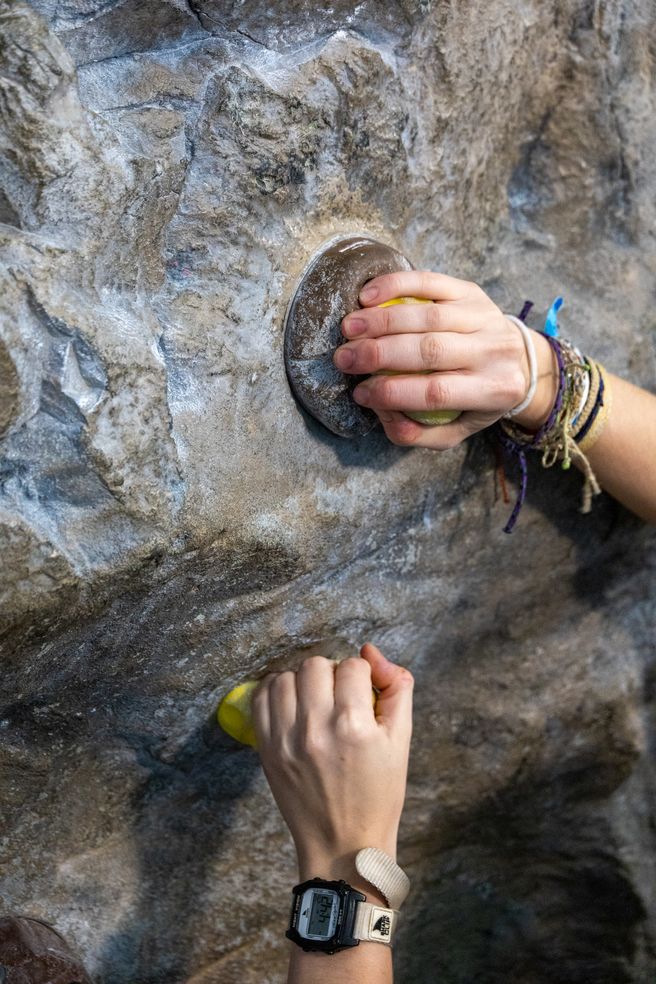 two hands grabbing on climbing wall